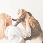 A delightful image of a woman sharing a loving moment with her fluffy cat, showcasing the joy of pet companionship.