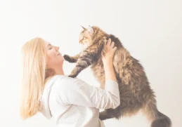 A delightful image of a woman sharing a loving moment with her fluffy cat, showcasing the joy of pet companionship.